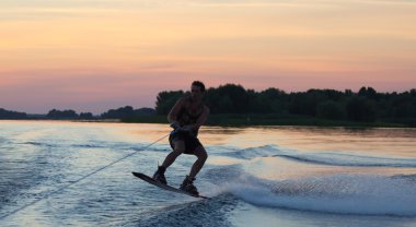 Wakeboarder günbatımı üzerinde hileler yapmak