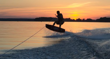 Wakeboarder günbatımı üzerinde hileler yapmak