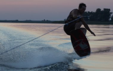 Wakeboarder günbatımı üzerinde hileler yapmak