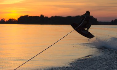 Wakeboarder günbatımı üzerinde hileler yapmak