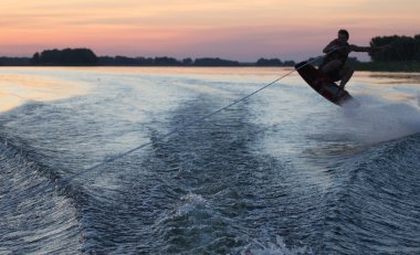 Wakeboarder günbatımı üzerinde hileler yapmak