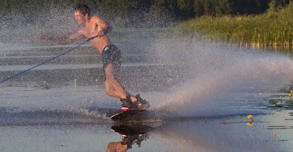 Wakeboarder athlète glisse dans l'eau avec spray brûlant — Photo