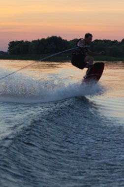 Wakeboarder günbatımı üzerinde hileler yapmak