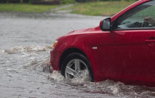 Passeios de carro em forte chuva em uma estrada inundada — Fotografia de Stock