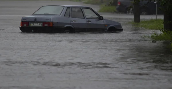 Auto rijdt in zware regen op een overstroomde weg — Stockfoto