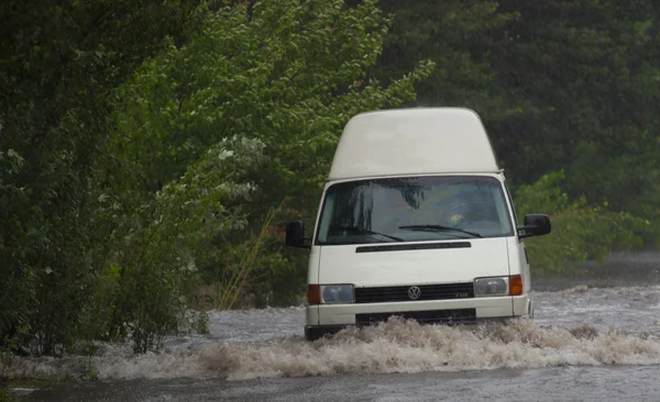 Автомобіль їде під сильним дощем на затопленій дорозі — стокове фото