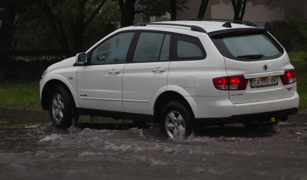 Автомобіль їде під сильним дощем на затопленій дорозі — стокове фото