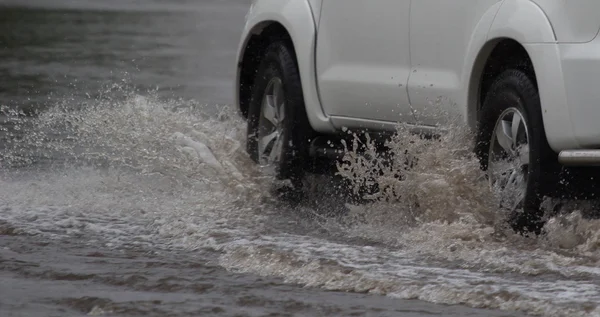 Passeios de carro em forte chuva em uma estrada inundada — Fotografia de Stock