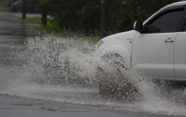 Passeios de carro em forte chuva em uma estrada inundada — Fotografia de Stock