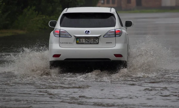 Автомобіль їде під сильним дощем на затопленій дорозі — стокове фото