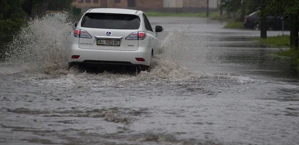 Passeios de carro em forte chuva em uma estrada inundada — Fotografia de Stock