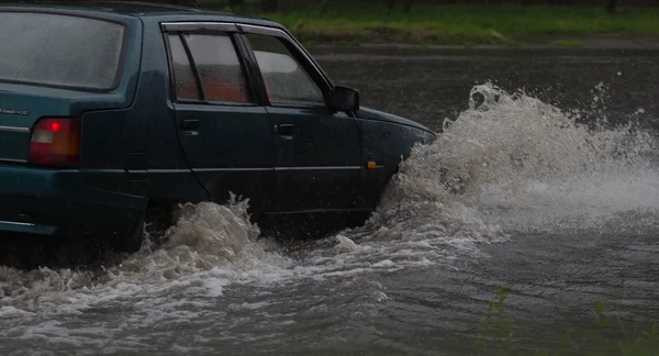 Auto rijdt in zware regen op een overstroomde weg — Stockfoto