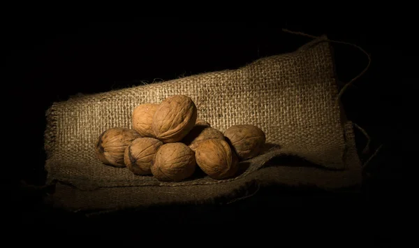 Walnusskerne und ganze Walnüsse auf rustikalem Sack. — Stockfoto