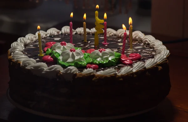 Ciasto z kolorowe świece w ciemności — Zdjęcie stockowe