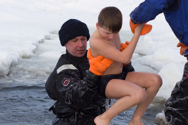 Cherkassy, Ukraine - January 19, 2016: lifeguard rescues a boy pulling it from the ice-cold water