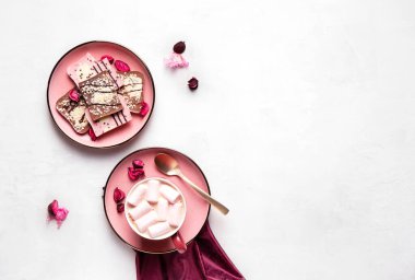 Gri zemin üzerinde pembe tabaklarda kremalı sıcak kahve ve çikolata düz zemin, yatay oryantasyon, kopyalama alanı