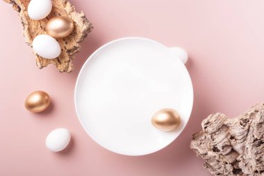 Beyaz ve altın Paskalya yumurtaları bir ağacın kabuğunda, beyaz bir plaka üzerinde tozlu bir zemin üzerinde, yatay yönelimde, kopyalama alanı