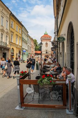 Krakow, Polonya - 29 Temmuz 2018: Polonya 'nın eski Krakow kentindeki St. Florian' s Gate 'deki Florianska Caddesi' nde bir kafede oturan turistler.