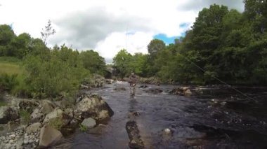 Minnoch, Galloway, İskoçya 'da hızla akan nehirde somon balığı avlarken bir balıkçı kancaya takılıp bir balıkla dövüşüyor.