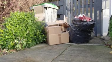 Bir adam, Noel 'de hediyelerini açtığı için çöp kutusunun yanına Noel ambalajı kağıdı atıyor.