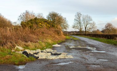 Tarımsal plastik atık kirliliği kırsal bir yolun kenarında, bir tarlanın kapısının yanında