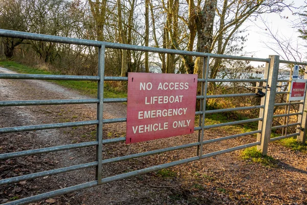 Red no access lifeboat emergency vehicle only sign on a gate by the coast in winter