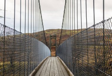 Kendoon Elektrik Santrali yakınlarındaki İskoç dağlık arazisindeki ahşap asma köprüyü izle