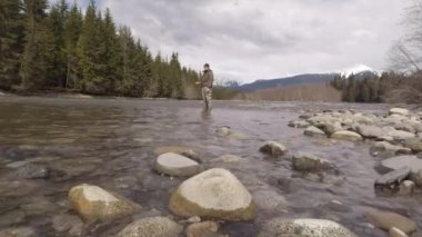 Skeena Bölgesi, Britanya Kolumbiyası, Kanada 'da bahar aylarında balık ve çelik kafa avlamak için nehre dökülen bir adam.