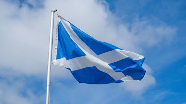 Aziz Andrew Haçı ya da hiciv, İskoçya 'nın ulusal bayrağı, rüzgarda dalgalanan arka planda mavi bir gökyüzü