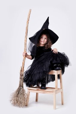 Beyaz arka planda beyaz arkaplanda süpürgesi olan komik cadı kız.