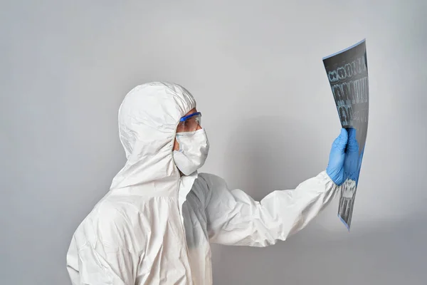 a doctor in a protective suit and mask looks at the results of a CT scan of the lungs to detect coronavirus.