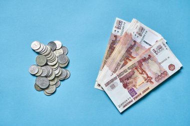 Birçok küçük Rus sikkesi ve mavi arka planda beş bin dolarlık banknotlar, para kavramı