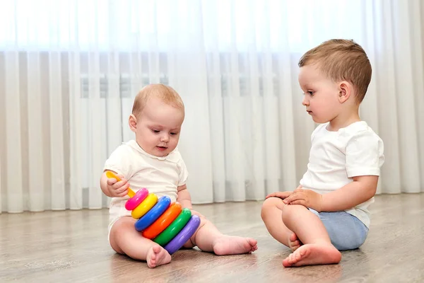 Zwei kleine Kinder mit blauen Augen spielen im Spielzimmer — Stockfoto