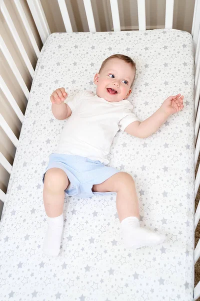 Uma criança pequena está deitada em uma cama infantil. vista superior — Fotografia de Stock