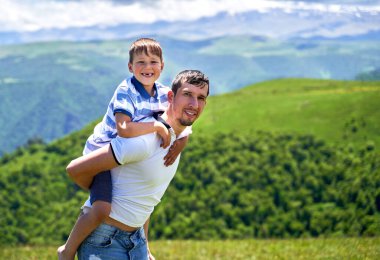 Bir çocuk babasının sırtına biner.