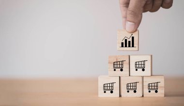 İş satış artışı ve mağaza bayiliği kavramını genişletmek, El 'in masaya tahta küp blok koyması, baskı ekran grafiği ve alışveriş arabası..