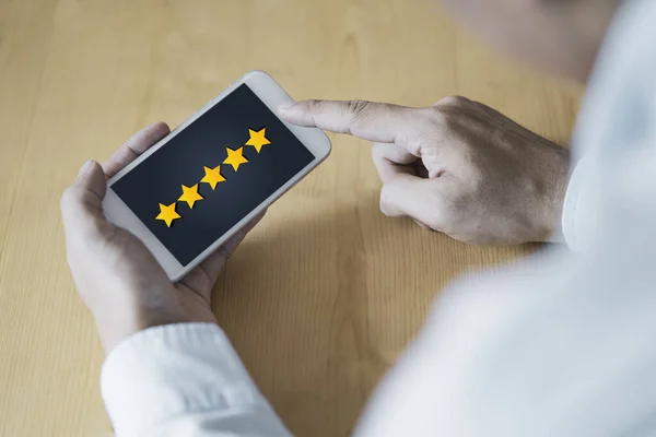 顧客満足と評価の概念 ビジネスマンは 使用後の製品やサービスを評価するためにスマートフォンに黄色の星を置く — ストック写真