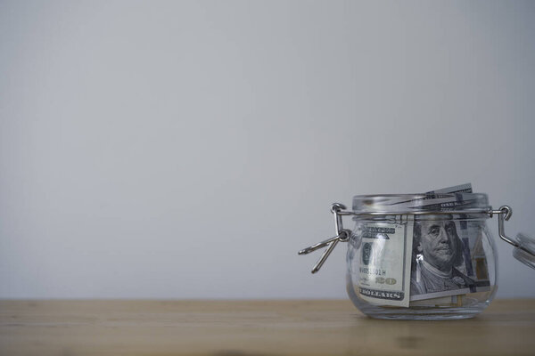 Банкнота на доллар внутри свиньи сберегает банку на деревянном столе и копирует пространство. Экономия доллара для инвестиционной концепции.
