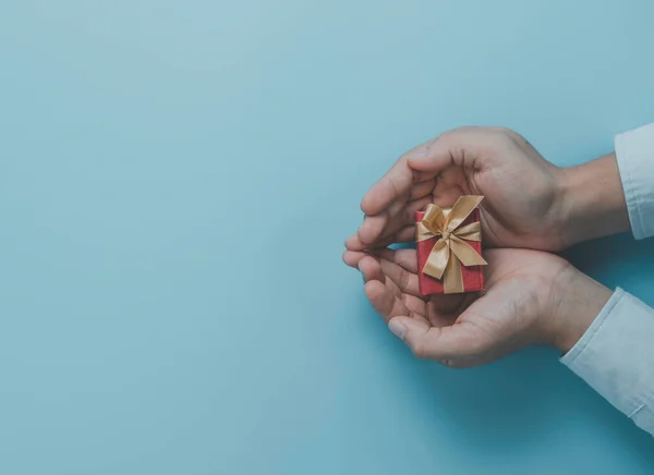 Businessman holding red gift box with gold ribbon for give present to lover , Merry Christmas Happy new year and valentine\'s day concept.