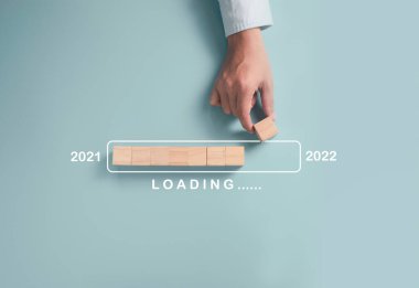 İş adamı 2021 'den 2022' ye kadar olan hazırlık süreci için tahta blok küpleri yerleştiriyor. Mutlu Noeller ve mutlu yıllar iş dünyası konsepti..