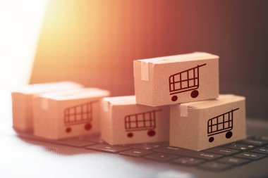 Trolley ya da alışveriş arabası logosu küçük kutular üzerinde çevrimiçi alışveriş ve müşteri konseptine servis için klavye bilgisayarı dizüstü bilgisayarı üzerinde yatıyordu.