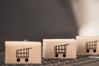Trolley ya da alışveriş arabası logosu küçük kutular üzerinde çevrimiçi alışveriş ve müşteri konseptine servis için klavye bilgisayarı dizüstü bilgisayarı üzerinde yatıyordu.