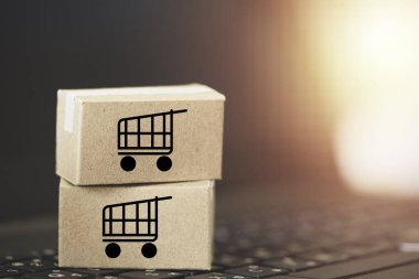 Trolley ya da alışveriş arabası logosu küçük kutular üzerinde çevrimiçi alışveriş ve müşteri konseptine servis için klavye bilgisayarı dizüstü bilgisayarı üzerinde yatıyordu.