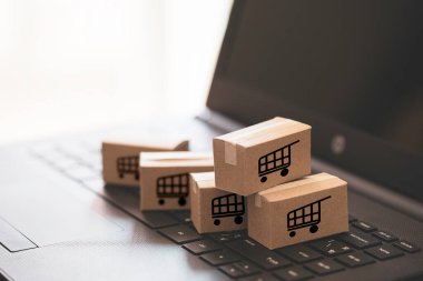 Trolley ya da alışveriş arabası logosu küçük kutular üzerinde çevrimiçi alışveriş ve müşteri konseptine servis için klavye bilgisayarı dizüstü bilgisayarı üzerinde yatıyordu.