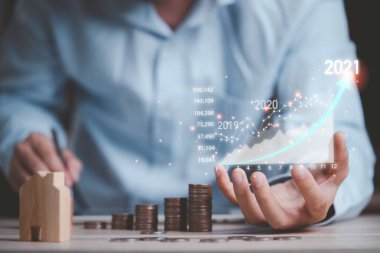 Sanal borsa grafiğini elinde tutan ve analiz etmek için hesap makinesi kullanan iş yatırımcısı, teknoloji kavramını kullanarak iş analizi yapıyor..