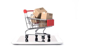 Kırmızı alışveriş arabasının içinde beyaz arka plan ve fotokopi alanı, çevrimiçi alışveriş ve e-ticaret konsepti olan tablet üzerindeki kargo kutularından izole edilmiş..