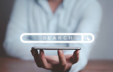 Sanal arama motoru tarayıcısı ve bilgi teknolojisi kavramına sahip akıllı telefonu elinde tutan bir iş adamı.