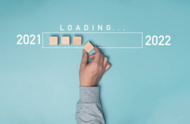 2021 'den 2022' ye kadar mavi arka plan, Mutlu Noeller ve mutlu yıllar konsepti üzerine bilgi yüklü tahta bloğu elle yerleştirmek.