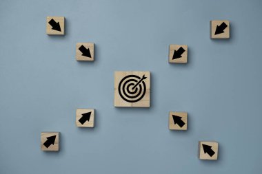 Sanal hedef tahtasını mavi arka planda ortala ve ok ekranı tahta küpte yazdır. İş başarısı hedefi ve hedef kavramı.