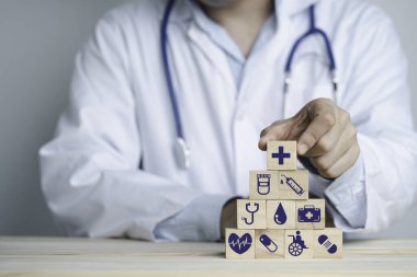 Doktor el, sağlık ve hastane ikonlarıyla ahşap istifleme masası, sağlık ve sigorta konseptini tutuyor..